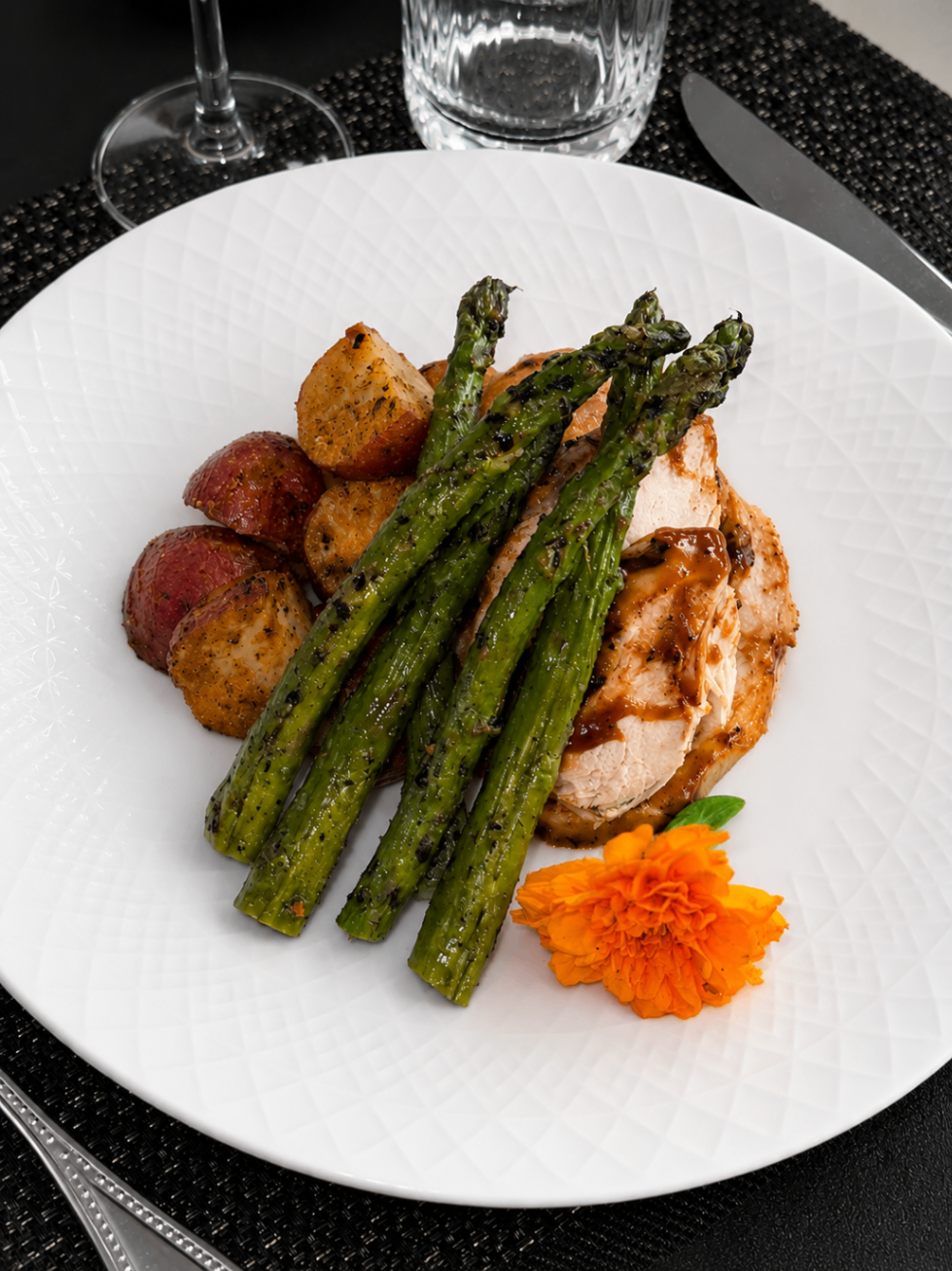 Plated entrée with asparagus, potatoes, and glazed chicken