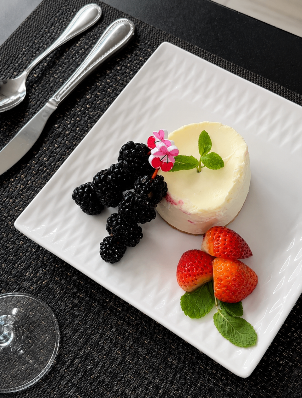 Plated cheesecake with berries and edible flower
